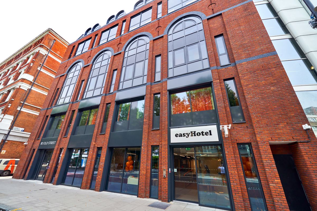 Exterior view of the easyHotel building at 80 Old Street, London, featuring red brickwork, large arched windows, and a prominent 'easyHotel' sign.