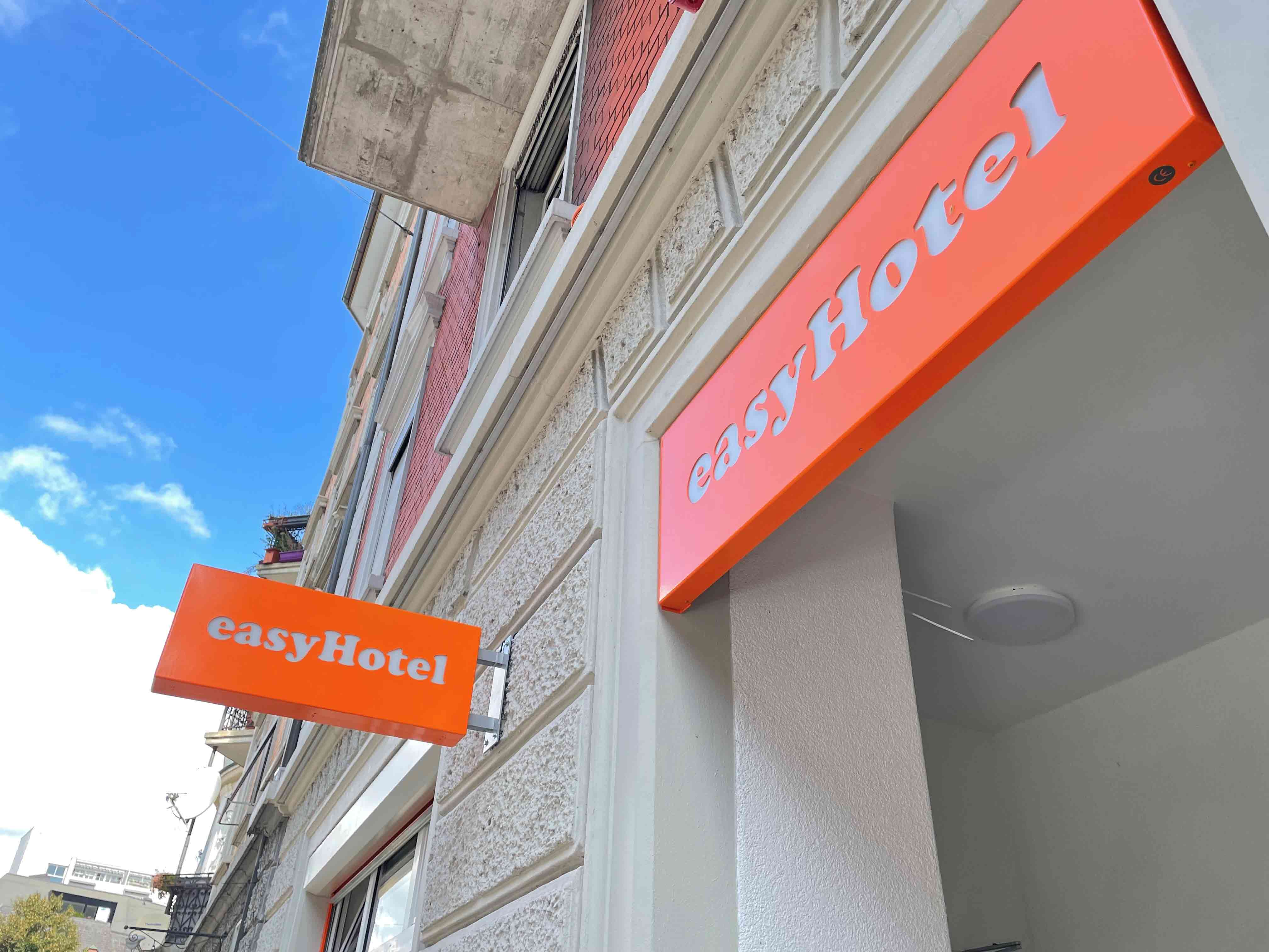 EasyHotel building exterior in Zurich, featuring its prominent orange signage against a blue sky.
