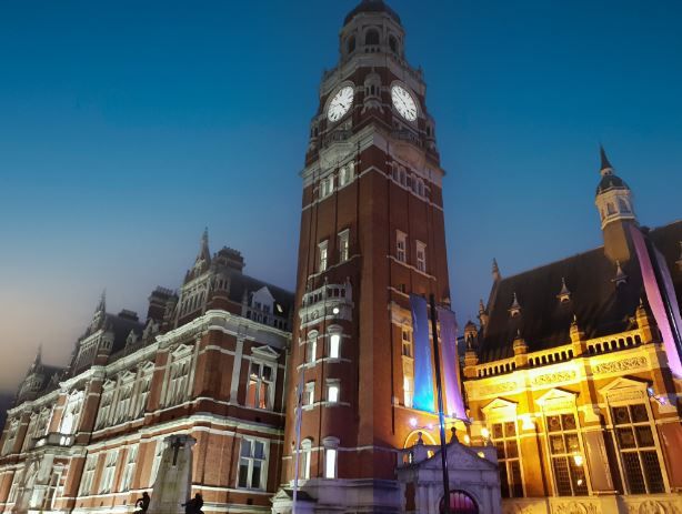 Croydon Town Hall at night, a historic Victorian building in South London with a prominent illuminated clock tower and warm lighting.