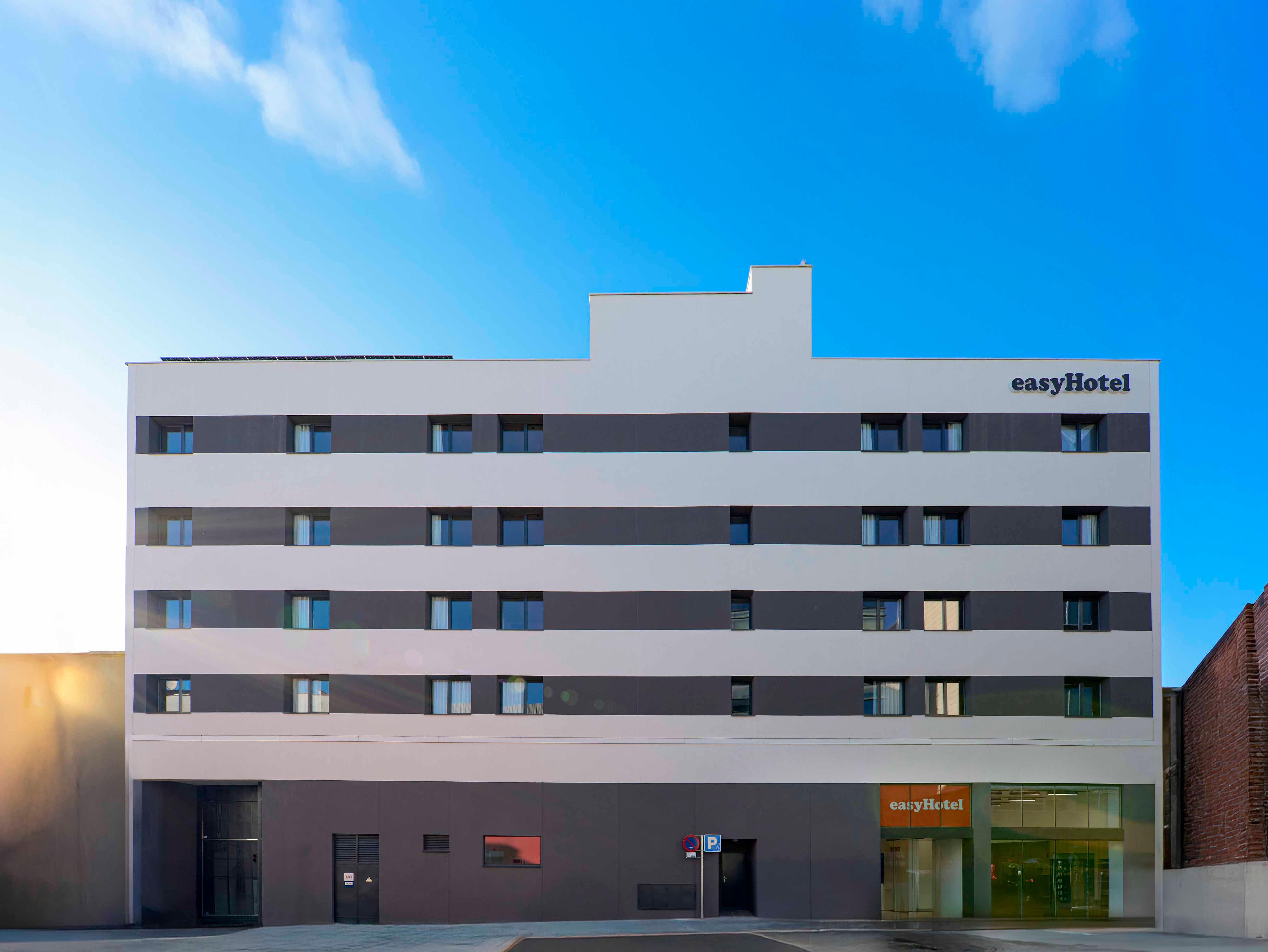 easyHotel Madrid Alcalá exterior view, a modern building with horizontal gray and white stripes and the easyHotel logo.