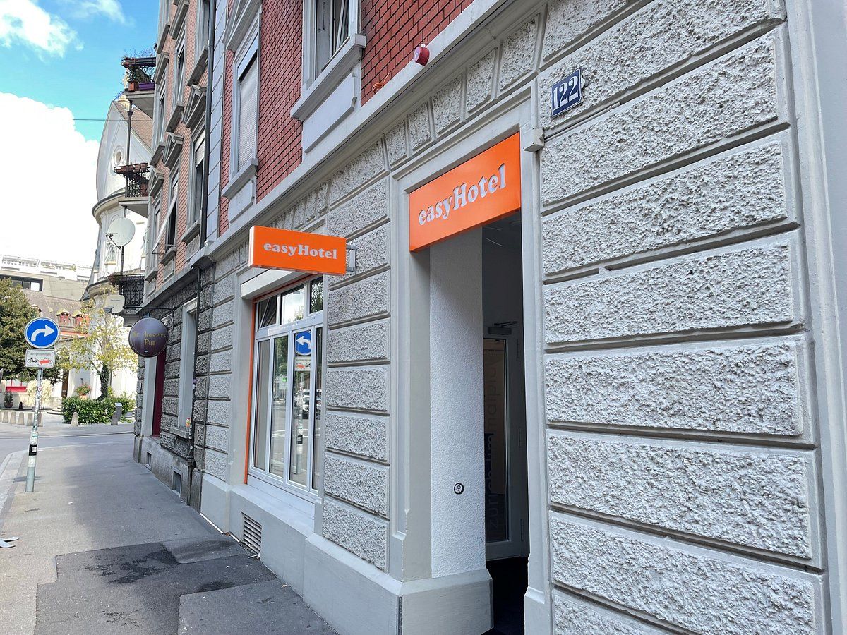 easyHotel Zurich Limmatplatz exterior featuring the orange hotel sign on a grey textured building facade, viewed from the street.