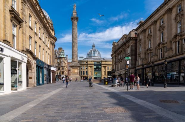 Grey's Monument and historic architecture dominate a bustling pedestrian street in Newcastle upon Tyne city center.